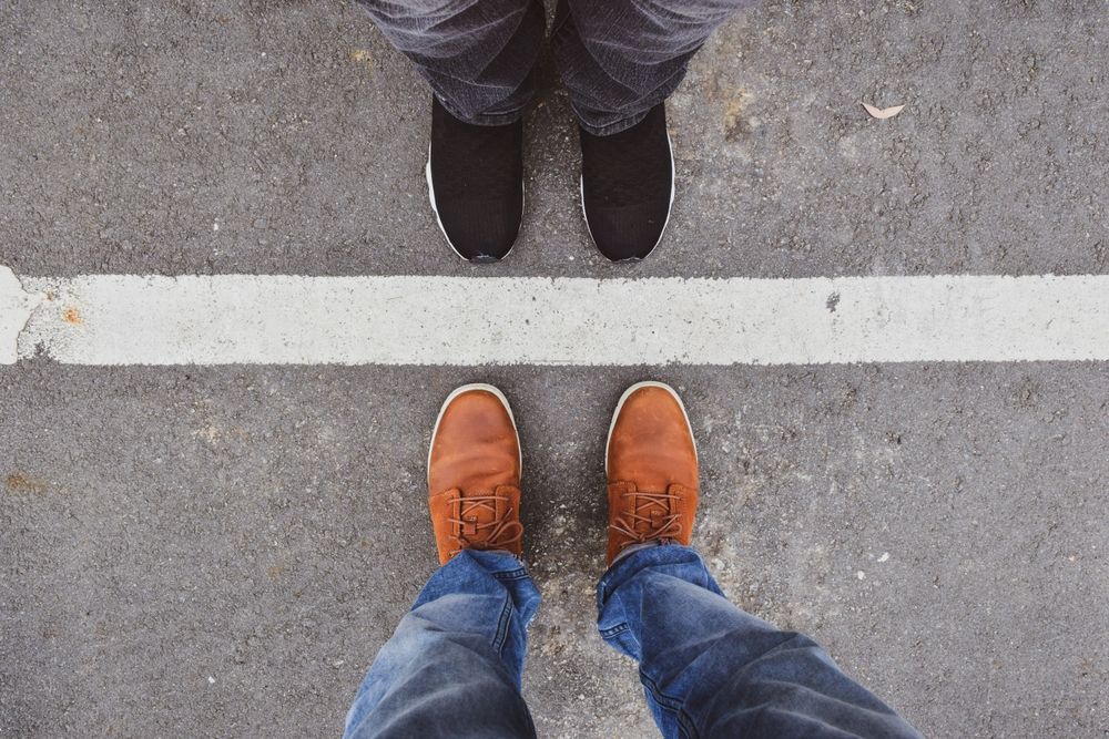 2 people standing facing each other with view of white line on ground