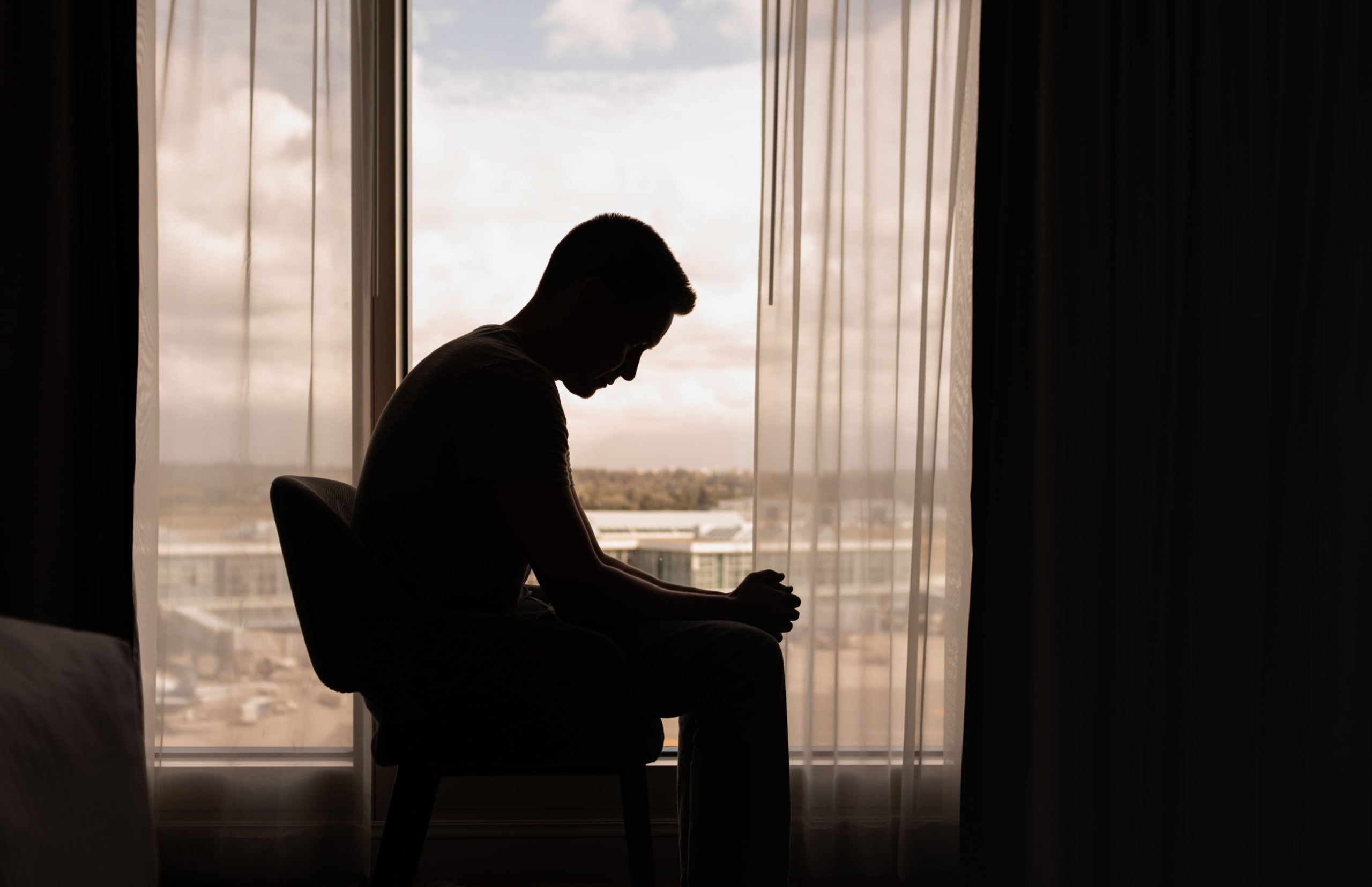 silhouette of a man in a dark room with head down.