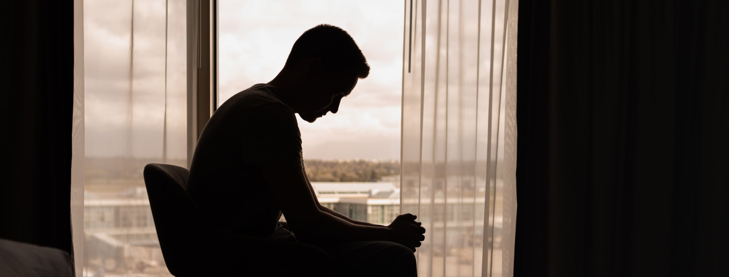silhouette of a man in a dark room with head down,