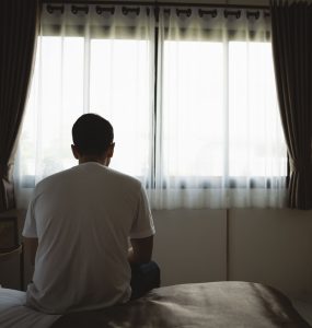 depressed man sadly sitting on the bed