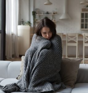 unhappy girl wrapped in warm plaid suffering from cold